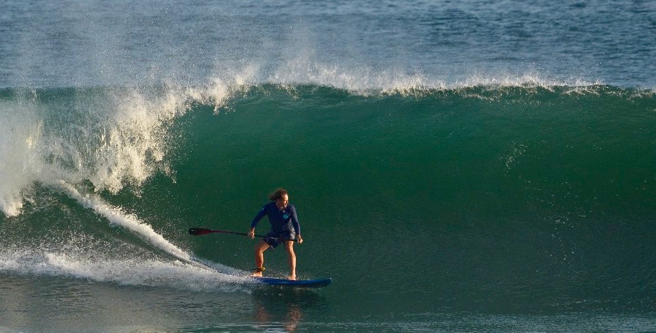 Dr. Aaron Burt riding inside a wave on a stand-up paddle board