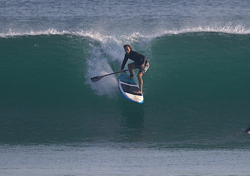 Surfer carving on a stand-up paddle board inside a breaking wave